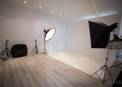 salle de shooting, fond blanc, sol bois clair gris, projecteurs et éclairages suspendus